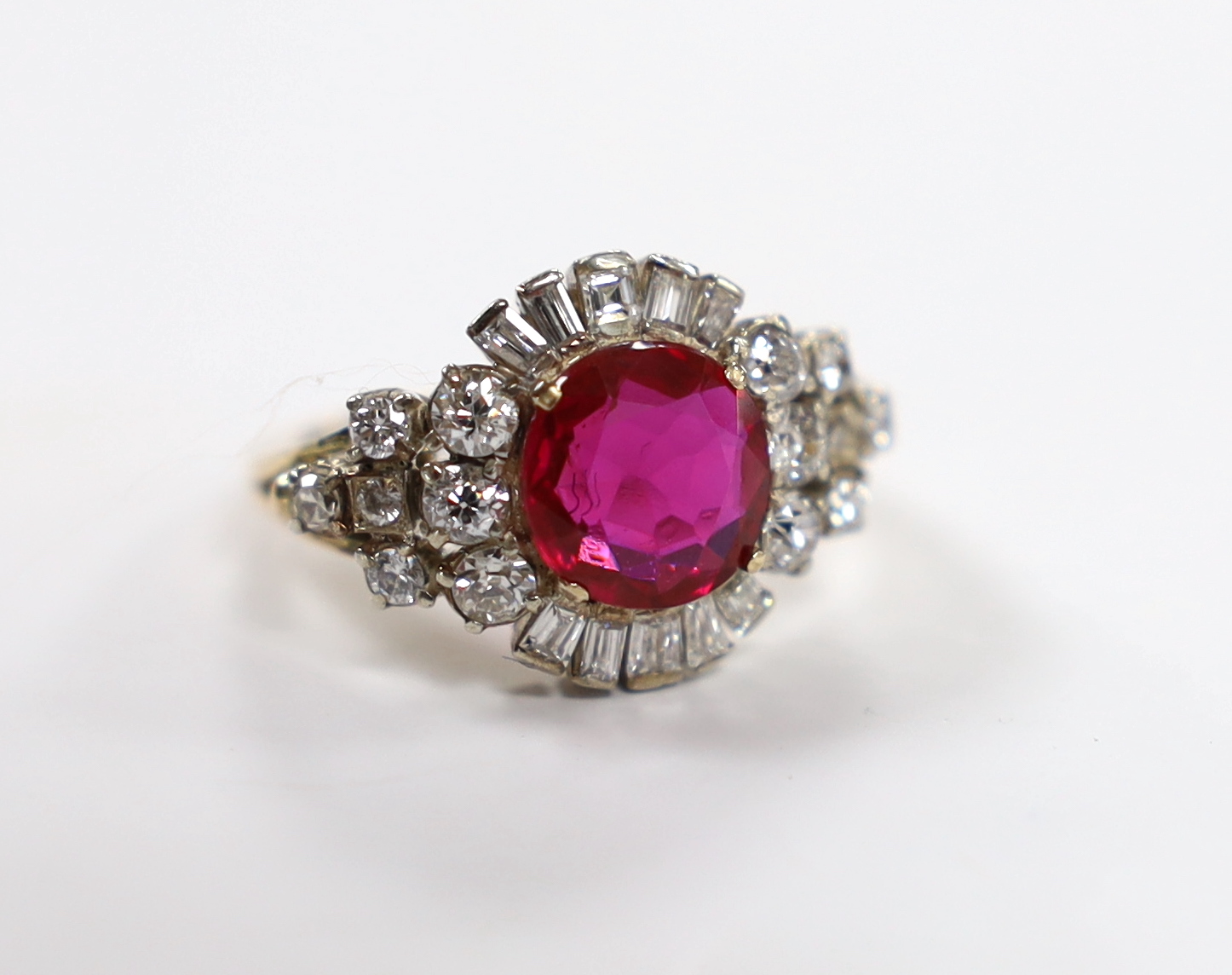 A yellow metal, singe stone round cut synthetic ruby and diamond set circular cluster dress ring, with diamond set shoulders, size J/K, gross weight 4.3 grams.